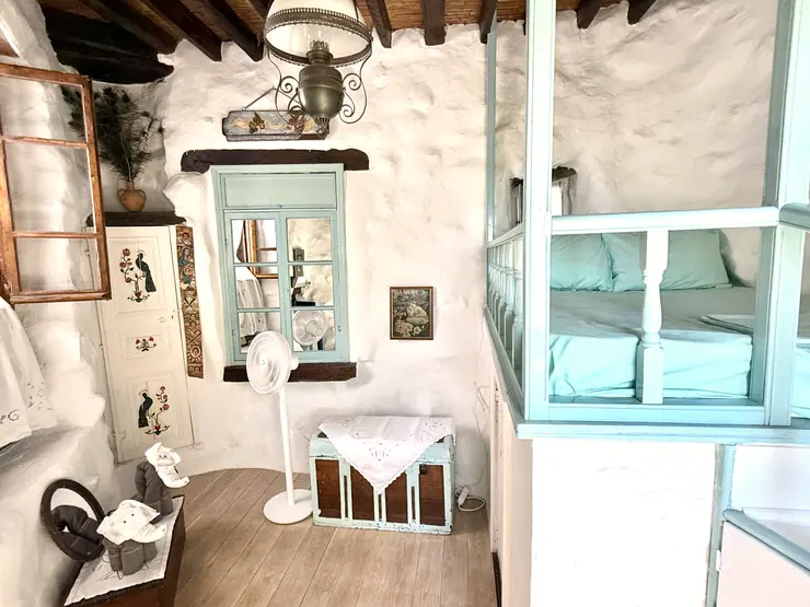 Green window shutters and timber details in a stone bedroom at Eco House Patmos