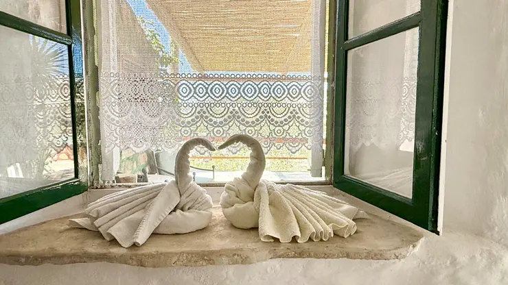 Folded towel swans on a bedroom windowsill overlooking the sea at Eco House Patmos