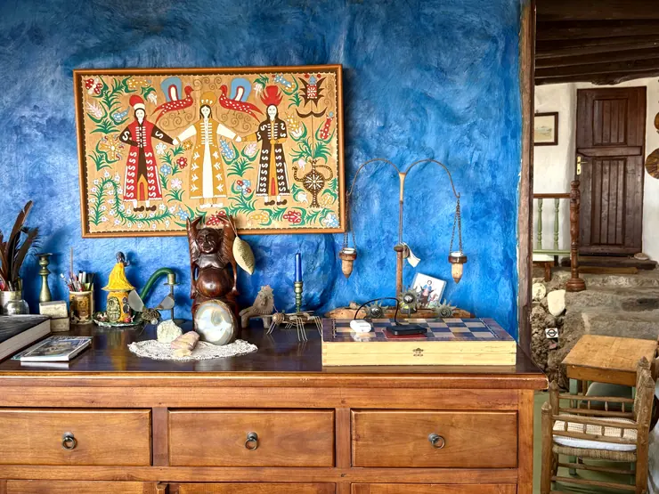 Colourful artwork and a small shrine against a blue wall at Eco House Patmos