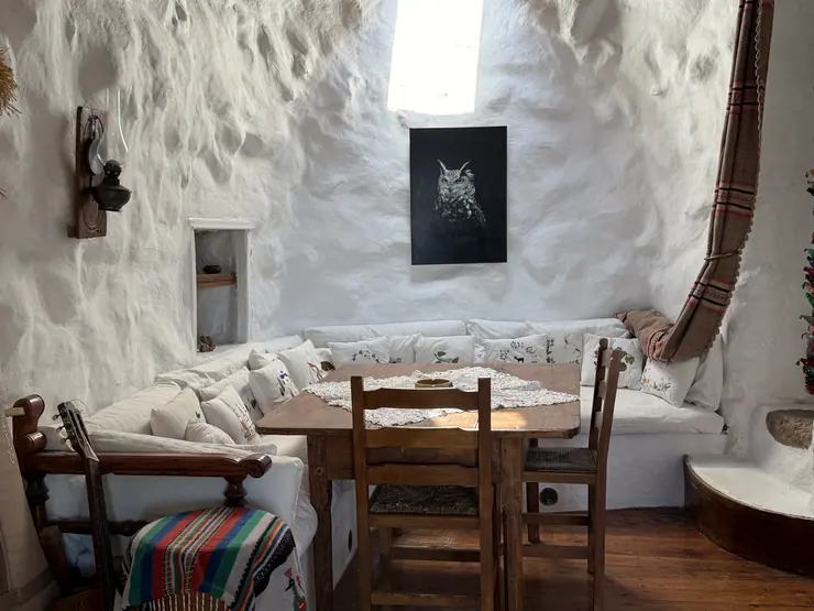 Wooden dining table and chairs against white stone walls at Eco House Patmos