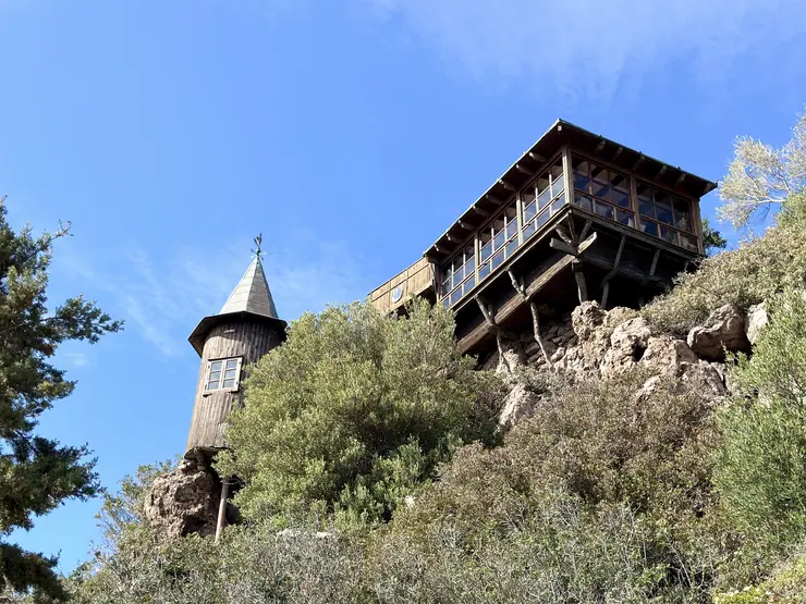 Wooden tower and glazed main house above the hillside garden at Eco House Patmos