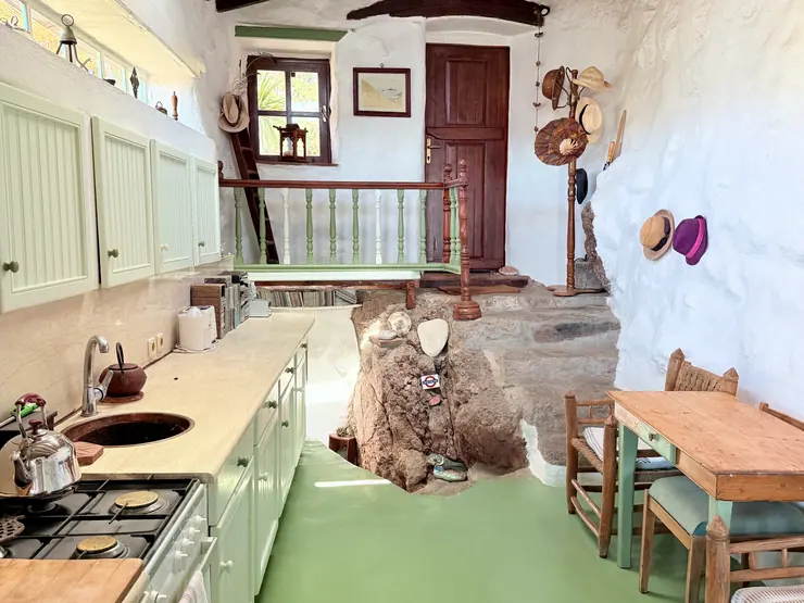 Kitchen counter and green cabinets beside exposed stone walls at Eco House Patmos