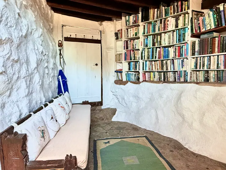 Bookshelves and built-in seating in a stone-walled living room at Eco House Patmos