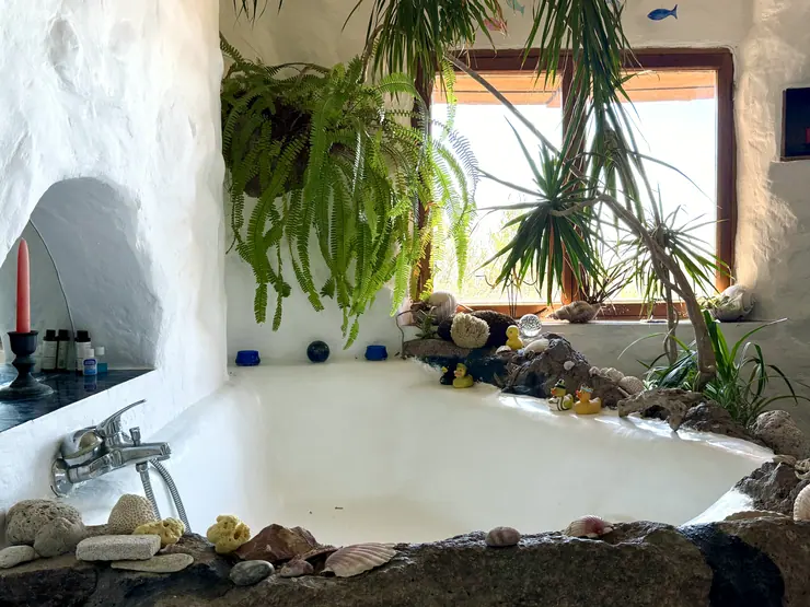 Built-in window seat with cushions and hanging plants at Eco House Patmos