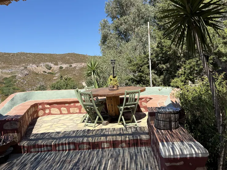 Outdoor dining table and chairs on a stone terrace at Eco House Patmos