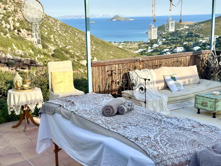 Massage table on a shaded outdoor terrace overlooking the sea at Eco House Patmos