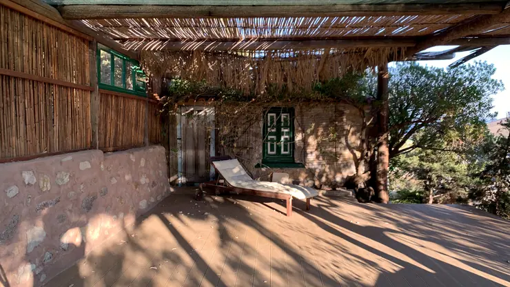 Shaded outdoor practice space with timber decking and a woven roof at Eco House Patmos