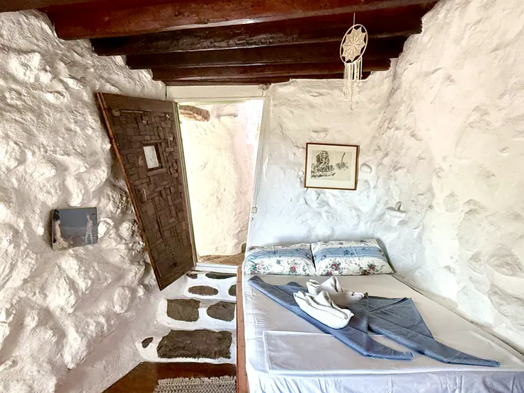 Single bed in a stone-walled bedroom with a timber ceiling at Eco House Patmos