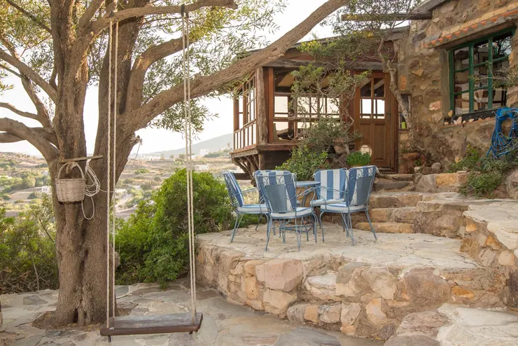 Eco House Patmos – stone terrace, table and swing beneath a tree