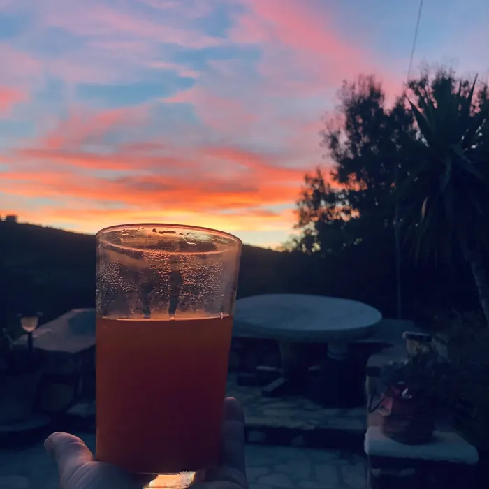 A drink held up to the Patmos sunset