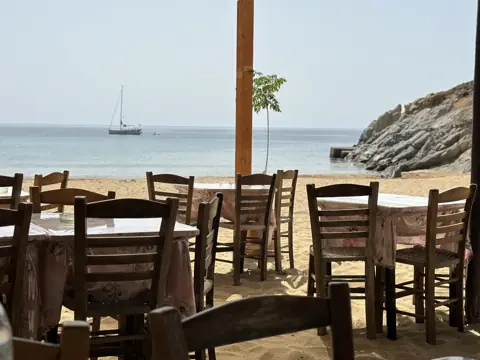 Wooden tables and chairs overlooking a Patmos beach