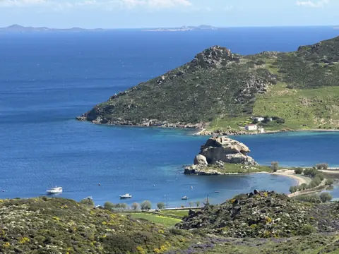 Green winter hills above a rocky Patmos coastline